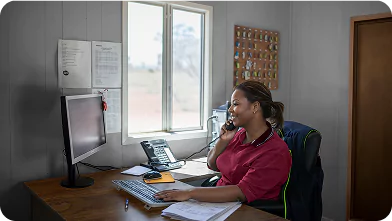 Front desk remote camp catering staff member answering a phone call at a remote camp office desk.