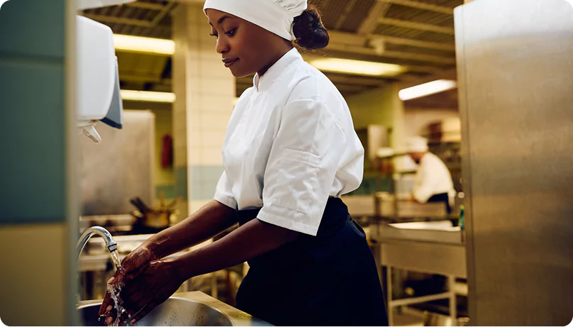 Private Workforce Camp Room at Remote Site Female kitchen staff member washing hands at a sink in a workforce accommodation camp kitchen to follow hygiene protocols.