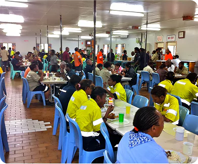 FIFO Workers Dining at Remote Camp Cafeteria in Africa FIFO workers in high-visibility clothing dining in a busy remote camp cafeteria in Africa.