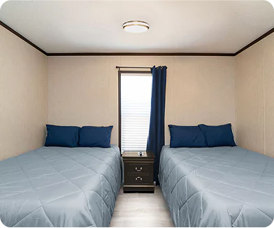 Two Bed Workforce Accommodation Room Modular camp room with two double beds and shared nightstand.