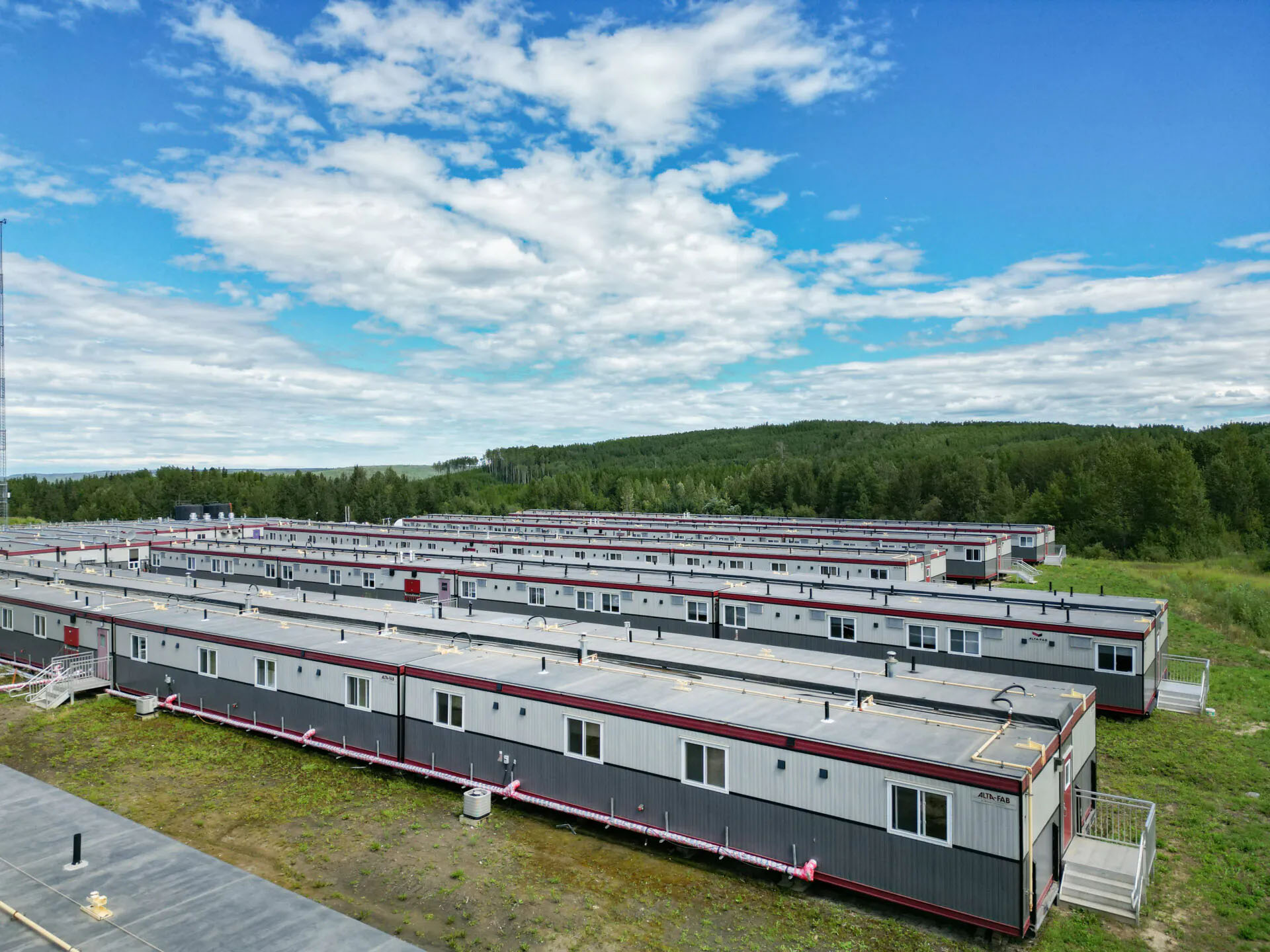 Aerial photograph of workforce lodging placed on a grassy field with trees and sky framing the photo.