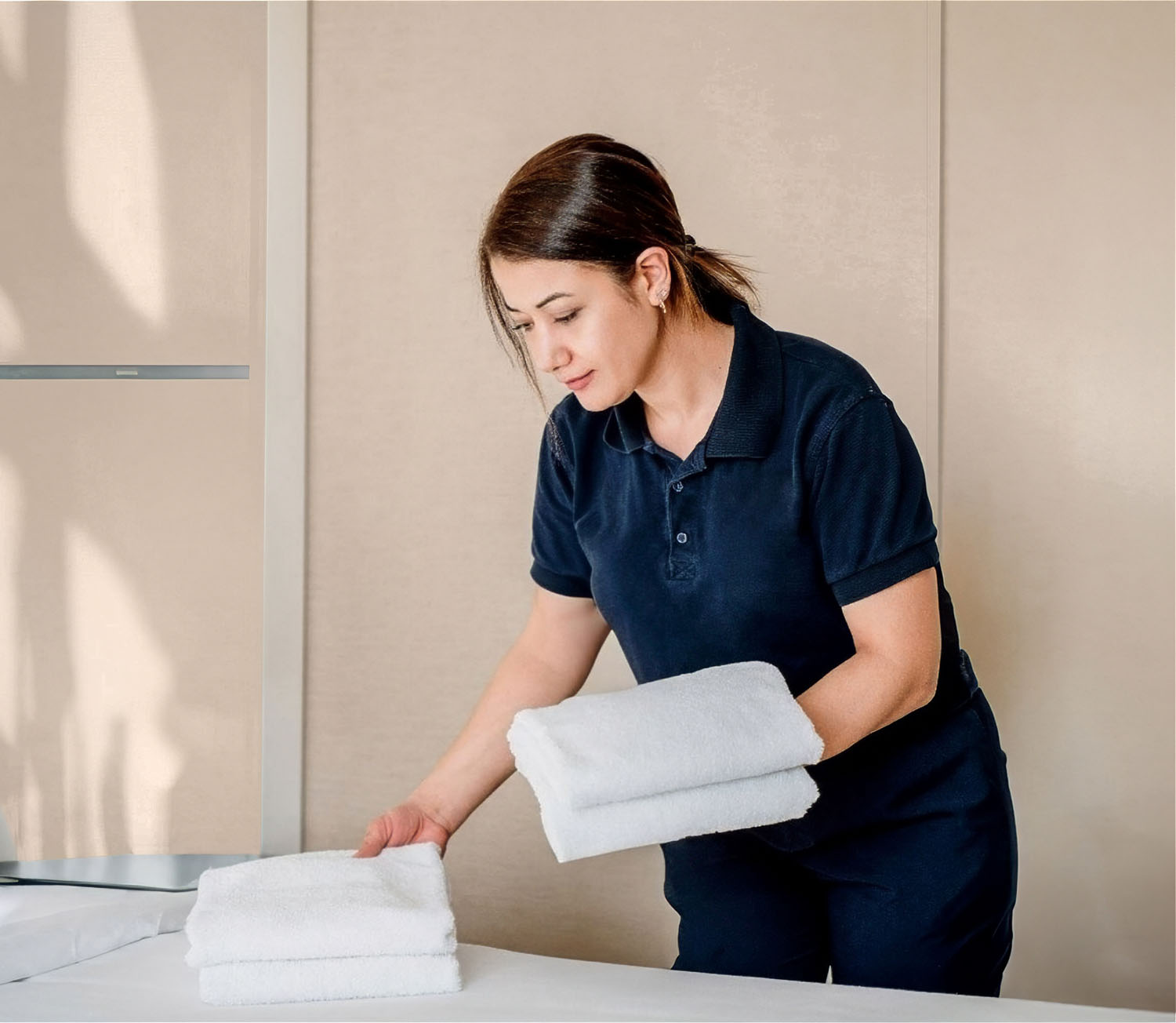 Cleaning staff places clean towels on a bed.