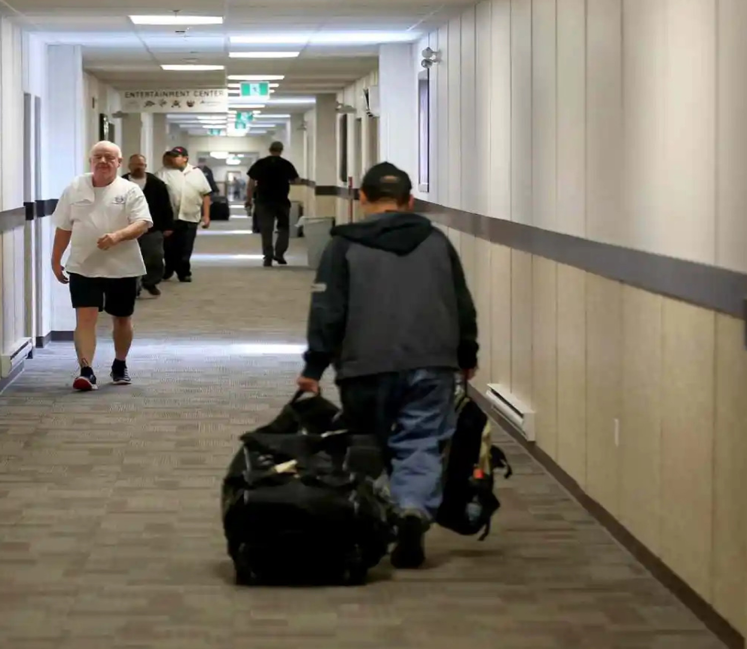 Workers walk down the long hallway of a work camp accommodation facility.