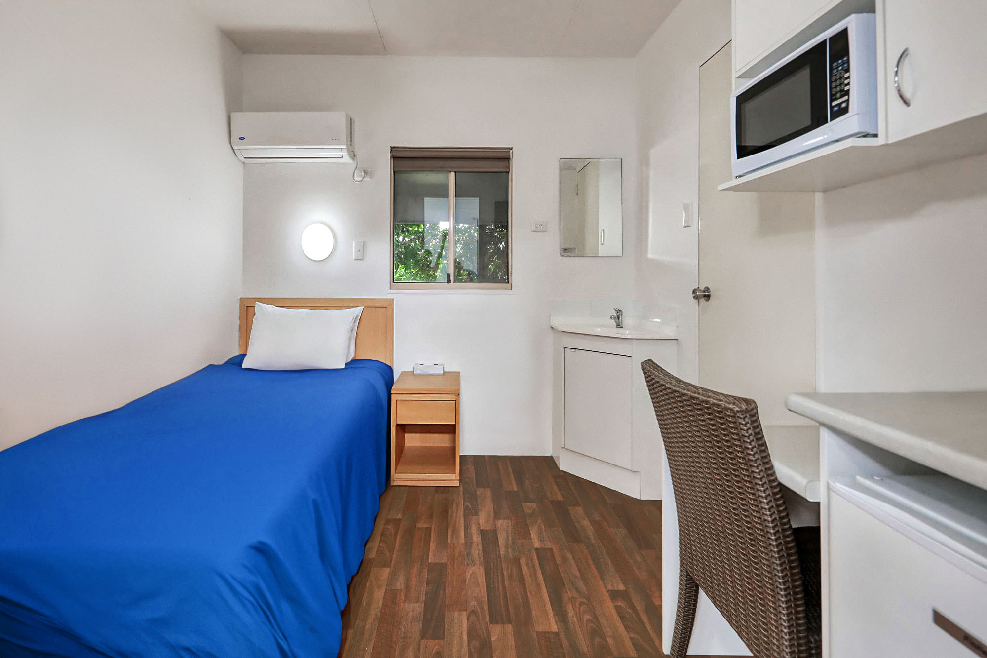 A bedroom with a bed, private sink and desk at a mining camp.