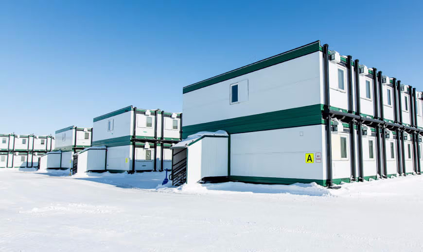 Rows of workforce camp buildings in a cold climate with snow on the ground outside.
